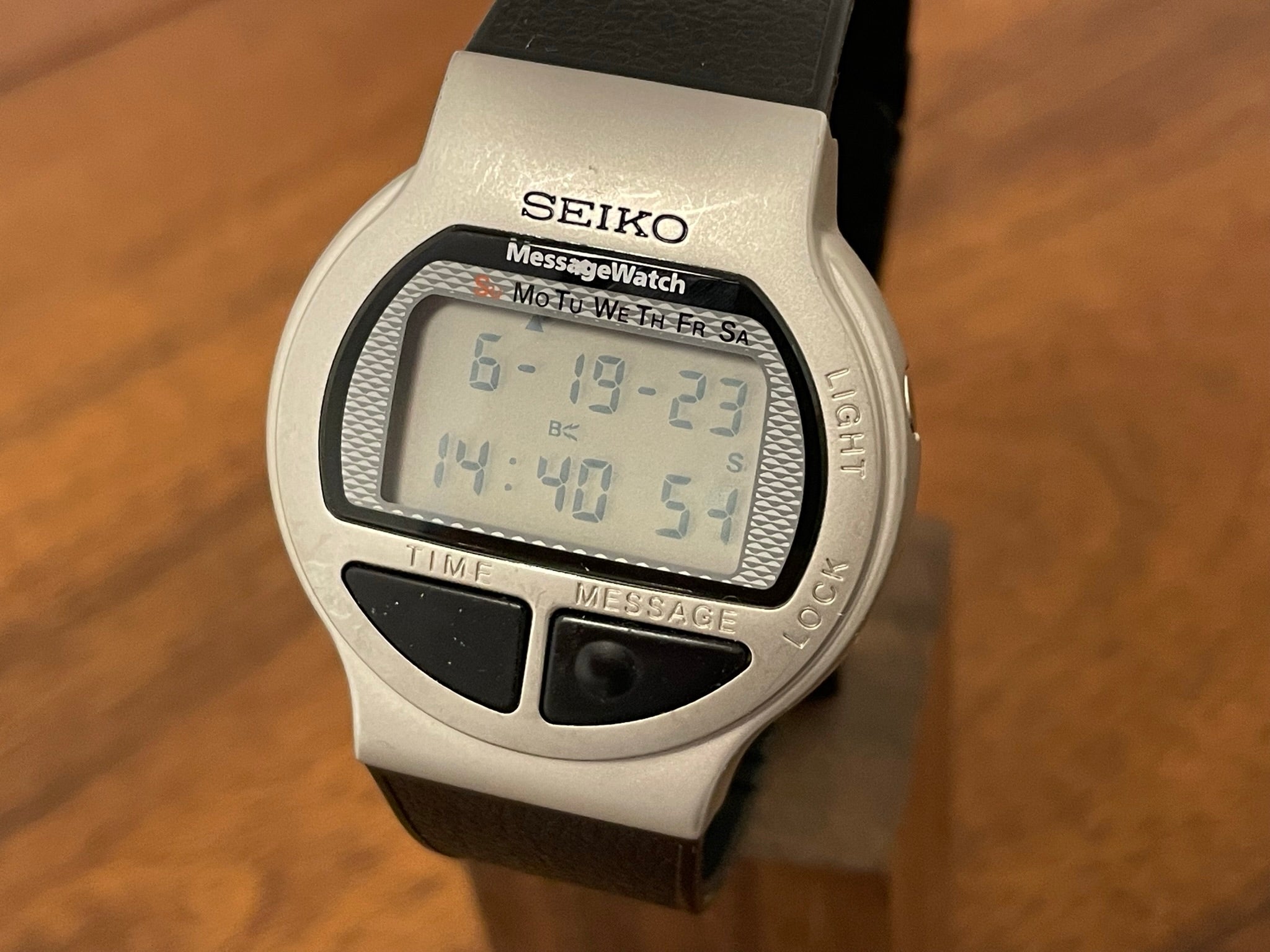 Image of a Seiko MessageWatch, with a grey frame, large black buttons and a traditional LCD display of the time period.